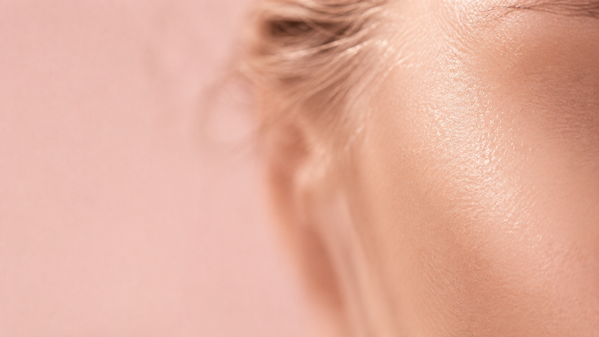 Gros plan sur une peau lumineuse, fond rose poudré